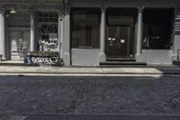 a brick walkway in front of a building with graffiti on it in the sunlight and a yellow umbrella by it