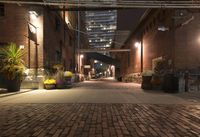 a brick walkway leading to several stores at night outside of an building in the city