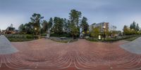 a photograph of a brick walkway with trees and buildings in the back ground around it