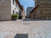 an empty street has bricks on the ground near buildings and a circle in the middle of the sidewalk