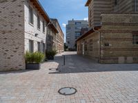 an empty street has bricks on the ground near buildings and a circle in the middle of the sidewalk