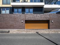 a brick wall in front of some buildings with a door and a brick driveway on the side