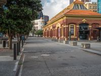 there is an empty city street with buildings in the background as clouds gather above it