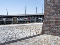 a brick wall near a road and bridge with a green fire hydrant in front