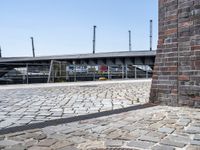 a brick wall near a road and bridge with a green fire hydrant in front