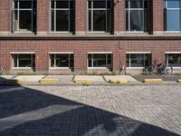 an empty brick driveway has three motorcycles parked by the front of it and bicycles in the background