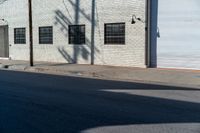 the shadow of a tree on the side of a building by a road with a car parked on it