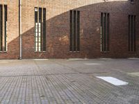 two street signs on brick walls near brick structure with windows and concrete patio below them