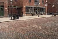 a brick walkway in front of an old building with a bench on the right side and a lamppost near the bottom