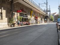 a city street with traffic on both sides and people sitting on the benches at the curb