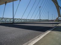 a truck driving across a bridge near a street corner near buildings and a bridge with many cables