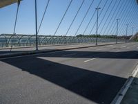 a truck driving across a bridge near a street corner near buildings and a bridge with many cables