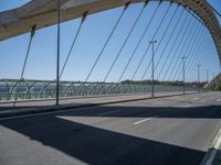 a truck driving across a bridge near a street corner near buildings and a bridge with many cables