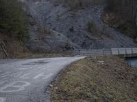 a bridge spanning the mountains to pass over a dirt road with a rock hill on either side