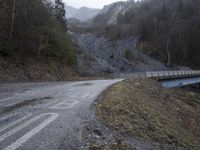 a bridge spanning the mountains to pass over a dirt road with a rock hill on either side