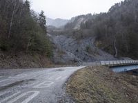 a bridge spanning the mountains to pass over a dirt road with a rock hill on either side