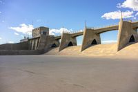 an overhead view of a concrete bridge and ramps on a cloudy day with blue skies above