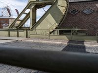 there is an unusual shaped bridge going across a brick street with buildings in the background