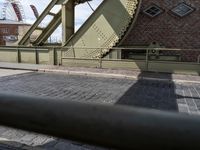 there is an unusual shaped bridge going across a brick street with buildings in the background