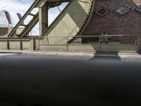 there is an unusual shaped bridge going across a brick street with buildings in the background