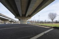 a bridge over a park with empty asphalt under a highway in the springtime time