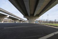 a bridge over a park with empty asphalt under a highway in the springtime time