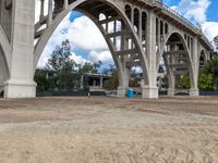 a dirt field under a bridge in an open area with two large concrete arches with no one on it