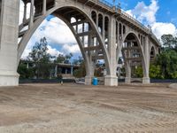 a dirt field under a bridge in an open area with two large concrete arches with no one on it