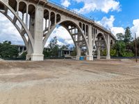 a dirt field under a bridge in an open area with two large concrete arches with no one on it