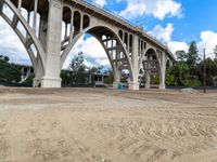 a dirt field under a bridge in an open area with two large concrete arches with no one on it