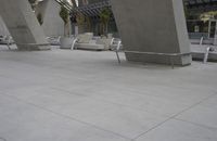a few chairs and benches sit under a bridge with large concrete pillars in the background