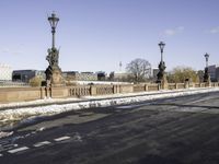 the statue is on the side of the bridge and has three street lamps on each end