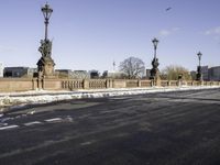 the statue is on the side of the bridge and has three street lamps on each end