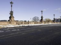 the statue is on the side of the bridge and has three street lamps on each end