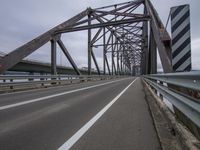 a bridge with a train going over it near the road on an overcast day