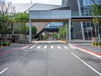 there is a bridge over the street near buildings and trees near it and some traffic signs