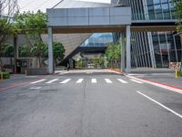 there is a bridge over the street near buildings and trees near it and some traffic signs