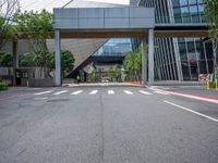 there is a bridge over the street near buildings and trees near it and some traffic signs