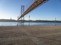 a long bridge that spans over water with a boat in the background, seen from the sidewalk area