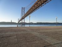 a long bridge that spans over water with a boat in the background, seen from the sidewalk area