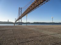 a long bridge that spans over water with a boat in the background, seen from the sidewalk area