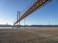 a long bridge that spans over water with a boat in the background, seen from the sidewalk area