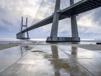 the view of a bridge from the ground of the water below it and over the pier