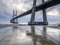 the view of a bridge from the ground of the water below it and over the pier