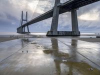 the view of a bridge from the ground of the water below it and over the pier