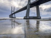 the view of a bridge from the ground of the water below it and over the pier