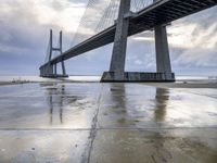 the view of a bridge from the ground of the water below it and over the pier