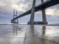 the view of a bridge from the ground of the water below it and over the pier