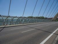 a truck driving across a bridge near a street corner near buildings and a bridge with many cables