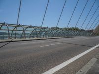 a truck driving across a bridge near a street corner near buildings and a bridge with many cables